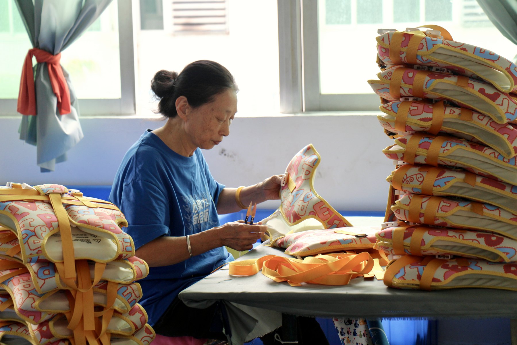 Worker checking finished neoprene swim vest products before shipment
